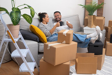 Unpacking and moving day become a celebration as a young couple cheers with coffee cups on the...
