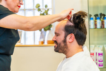 Obraz premium Happy client resting while hairdresser attaching a capillary prosthesis