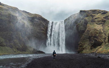 Inspiring Skogafoss waterfall. Icelandic natural wonder with majestic waterfall and rugged surroundings. Cold water, cloudy sky, Nordic atmosphere.