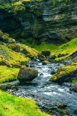 Rock walls covered with grass and moss. Bright colours, uncontrolled nature. Breathtaking Icelandic views, trails, Nordic atmosphere. Volcanic lands.
