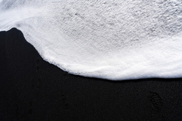 White foam on black sand. Sea in Iceland, volcanic beach. Single color, curves, water, ocean,...