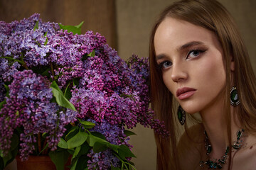 portrait of a beautiful young girl with exquisite makeup with a bouquet of lilacs