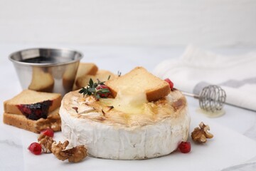 Tasty baked camembert with crouton, thyme, walnuts and pomegranate seeds on white table, closeup