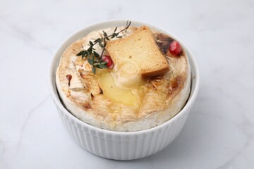 Tasty baked camembert with crouton and thyme on white marble table, closeup