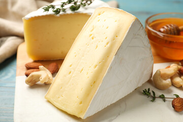 Tasty Camembert cheese with thyme, honey and nuts on light blue wooden table, closeup