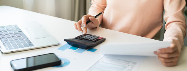Deduction planning, debt asian young woman  hand using calculator to calculating money balance from bill and income, cost budget expenses for pay money form personal individual on table at home.