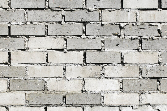 Gray uneven bricks. Home building background. Bricklayer bad job. Cement grout fugue. Masonry texture.