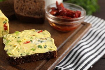 Tasty butter with green onion, chili pepper and rye bread on table, closeup