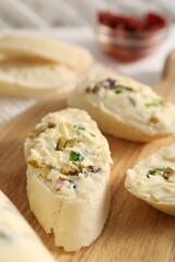 Tasty butter with olives, green onion and bread on wooden board, closeup