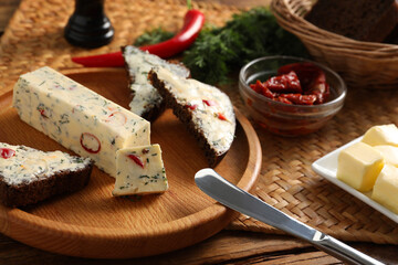 Tasty butter, dill, chili peppers and rye bread on wooden table