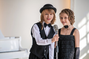 Two young children in formal wear sing a duet into a microphone.