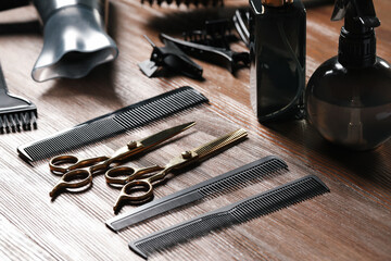 Hairdresser tools. Different scissors and combs on wooden table, closeup