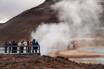 Tourists explores Námafjall Geothermal Area. Group of hikers on an observation point admire the...