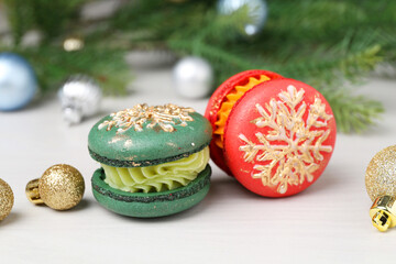 Obraz premium Different decorated Christmas macarons and festive decor on white wooden table, closeup