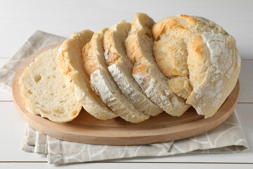 Freshly baked cut sourdough bread on white wooden table