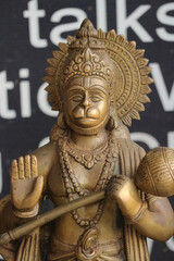 Obraz premium Bronze figurine of Hanuman with a mace and a blessing gesture on a dark background.