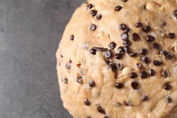 Raw dough with chocolate chips on grey table, top view. Space for text