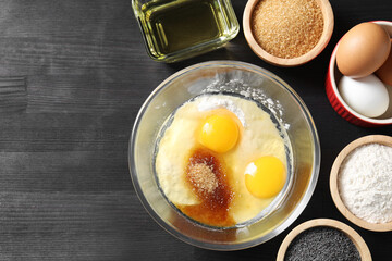 Ingredients for homemade dough on black wooden table, flat lay. Space for text