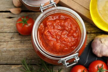 Homemade tomato sauce in jar on wooden table, top view