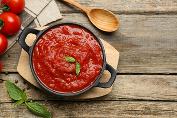 Homemade tomato sauce in bowl, spoon and fresh ingredients on wooden table, flat lay. Space for text