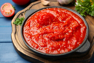 Homemade tomato sauce in bowl on blue wooden table, closeup