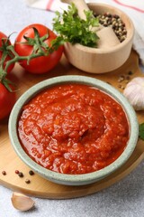 Homemade tomato sauce in bowl and fresh ingredients on light grey table