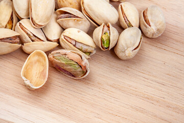 
Pistachios scattered on wooden surface with copy space
