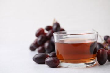 Wine vinegar in glass bowl and grapes on light grey table, space for text