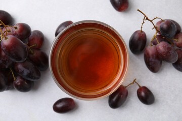 Wine vinegar in glass bowl and grapes on light grey table, flat lay