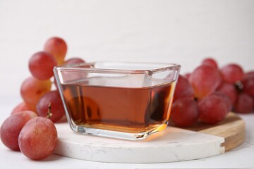Wine vinegar in glass bowl and grapes on white table