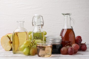 Different types of vinegar and ingredients on wooden table, closeup