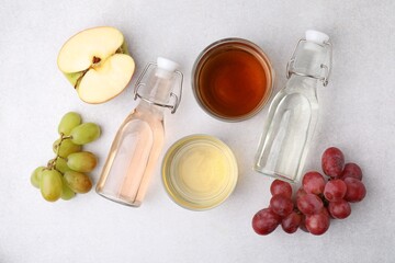 Different types of vinegar and ingredients on light table, flat lay