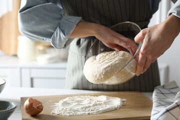 Woman kneading dough at white wooden table in kitchen, closeup