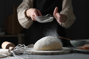 Making dough. Woman sifting flour at grey table, closeup