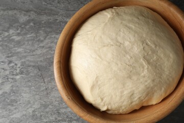 Raw dough in bowl on grey table, top view