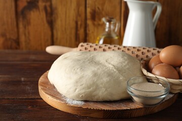 Raw dough, rolling pin and ingredients on wooden table