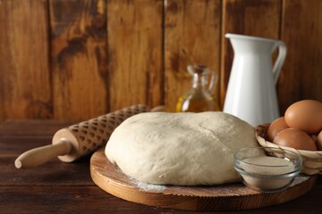 Raw dough, rolling pin and ingredients on wooden table