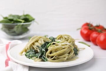 Tasty pasta with spinach and sauce on white tiled table, closeup