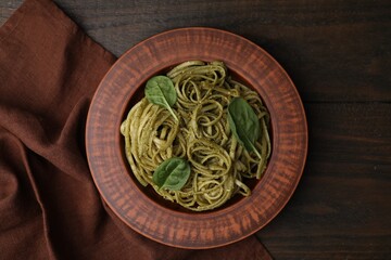 Tasty pasta with spinach on wooden table, top view