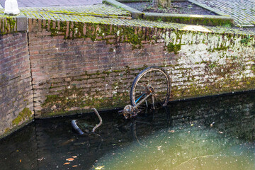 An old bicycle lies in the water in a city canal called Gracht in the Netherlands, Delft, 25 March...