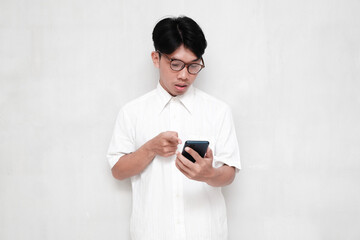 Fototapeta premium Asian man in white shirt shocked pointing at cell phone