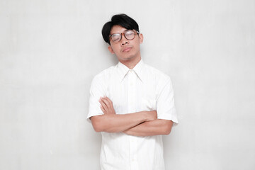 Young Asian man wearing white shirt and glasses on white background thinking looking tired and...