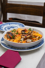 A traditional Alentejo restaurant serves a vibrant seafood feijoada. This dish features prawns, shellfish, and beans in a rustic clay pot, offering a hearty and authentic Portuguese experience.