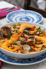 A traditional Alentejo restaurant serves a vibrant seafood feijoada. This dish features prawns, shellfish, and beans in a rustic clay pot, offering a hearty and authentic Portuguese experience.