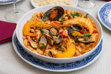 A traditional Alentejo restaurant serves a vibrant seafood feijoada. This dish features prawns, shellfish, and beans in a rustic clay pot, offering a hearty and authentic Portuguese experience.