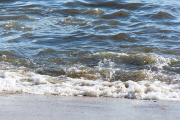 Low view of waves breaking on the beach sand on a cloudy day.