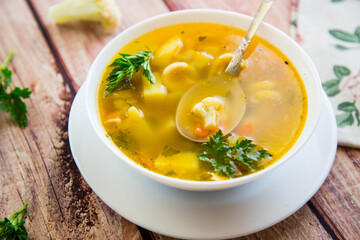Homemade chicken vegetable soup on rustic wooden background