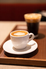 A white coffee cup with a brown rim sits on a brown tray