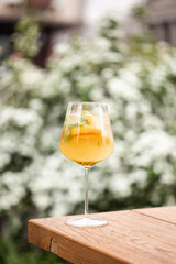 Exotic Passion Fruit and Peach Summer Cocktail in a Wine Glass - Refreshing Drink Garnished with Mint Leaves, Served in an Outdoor Garden Setting