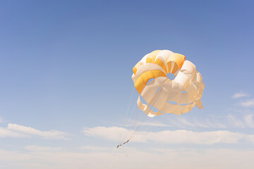 The parachute is fully inflated, showcasing vivid yellow and white colors as it glides through the...